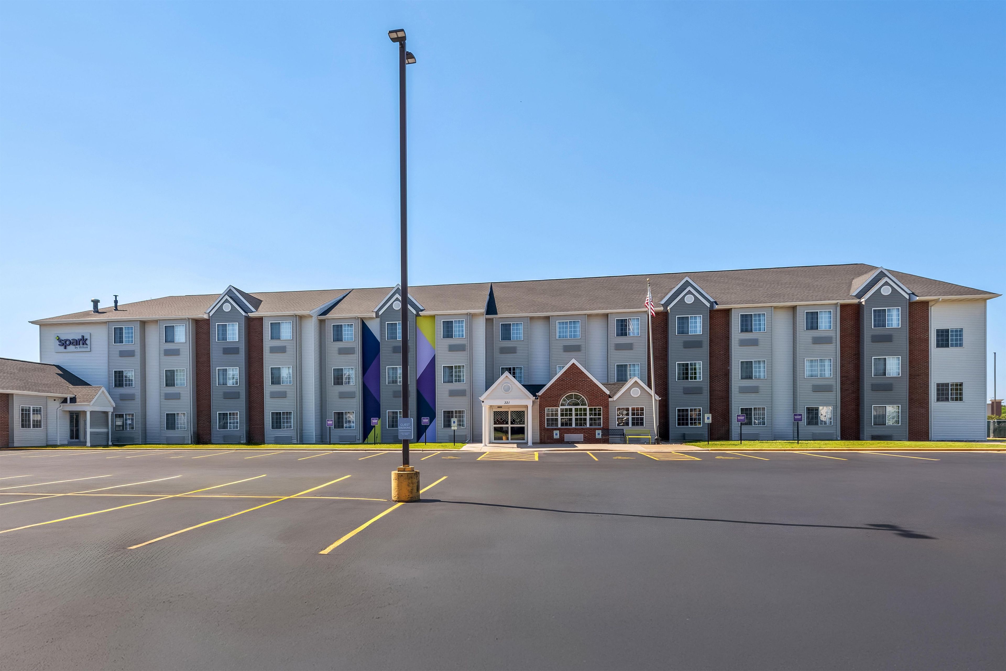 A multi-story hotel with a parking lot in front.