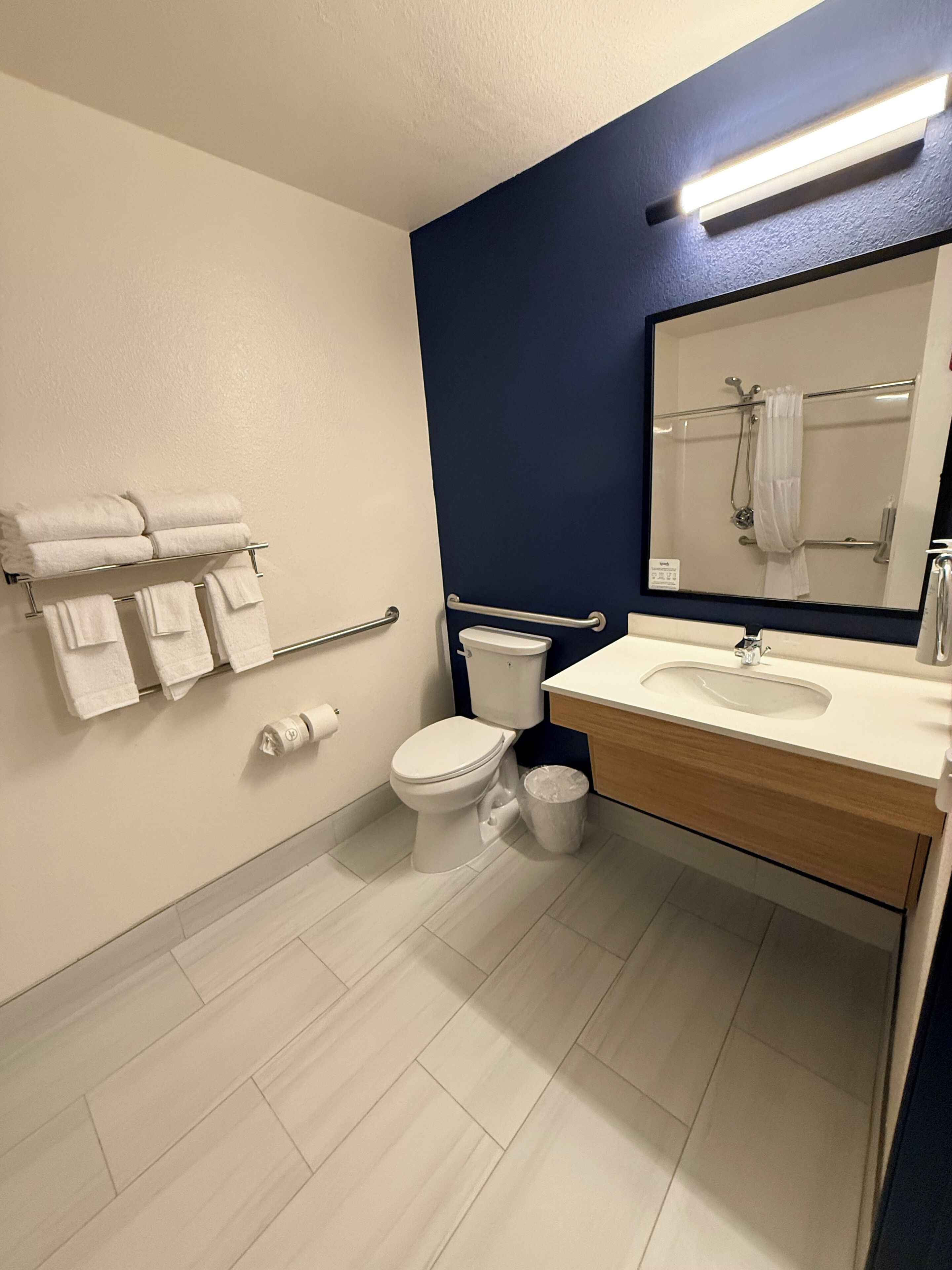 A modern bathroom with a white toilet, a sink with a mirror, and a towel rack.