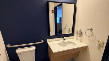 A bathroom with a white toilet, a sink with a mirror above it, and a blue wall.