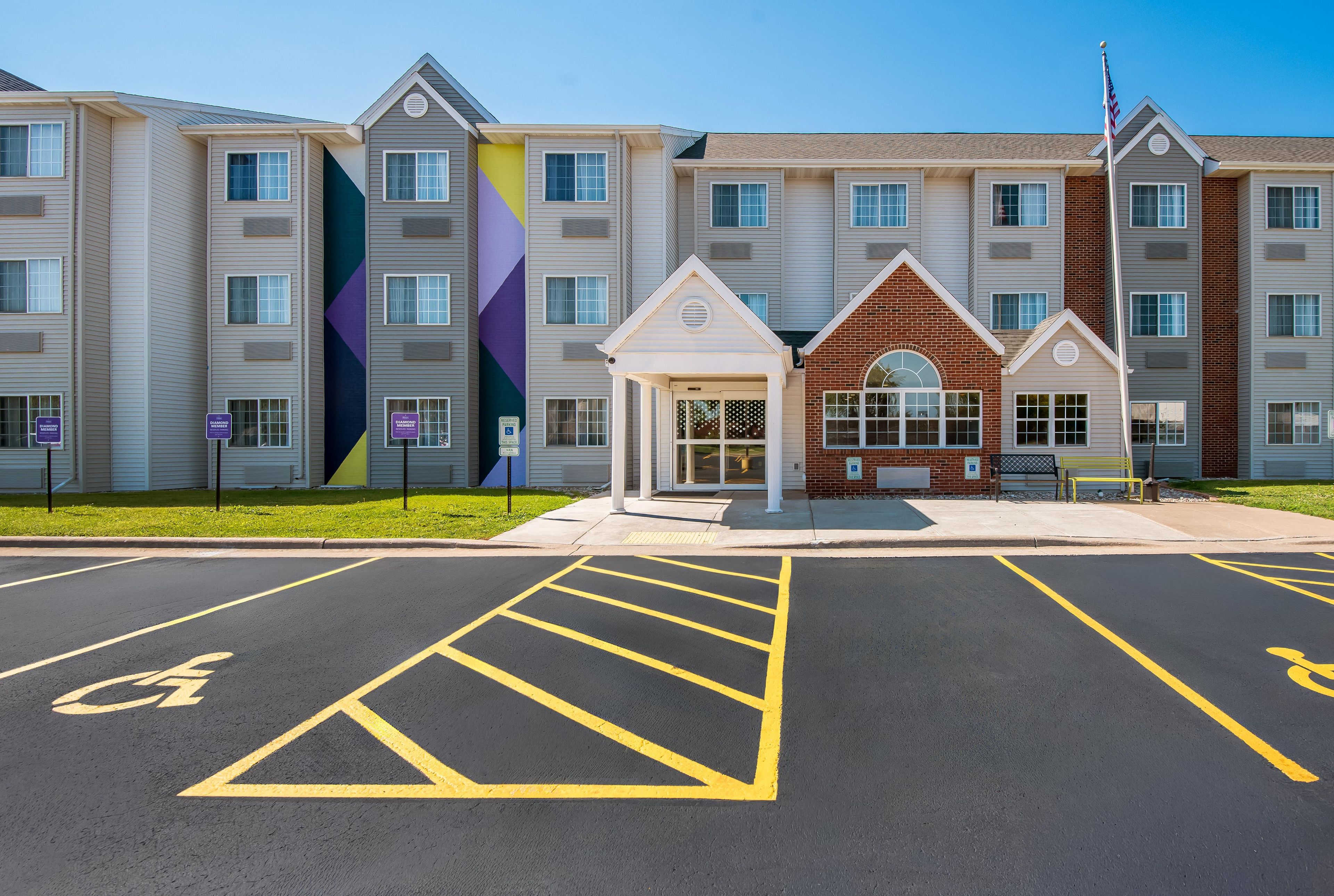 A multi-story hotel with a parking lot in front, marked with handicapped parking spaces.