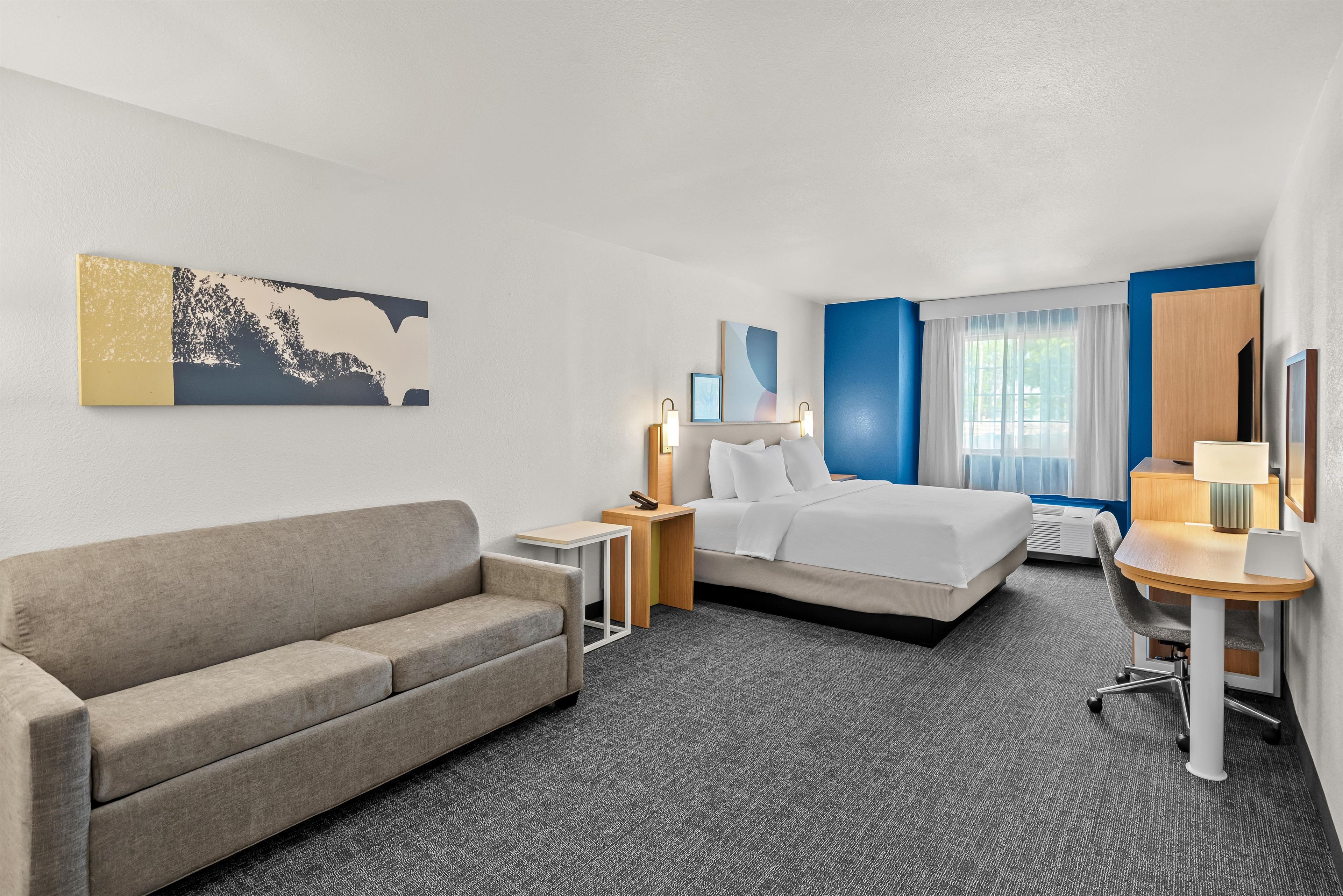 Una habitación de hotel con cama, sofá, escritorio y silla.