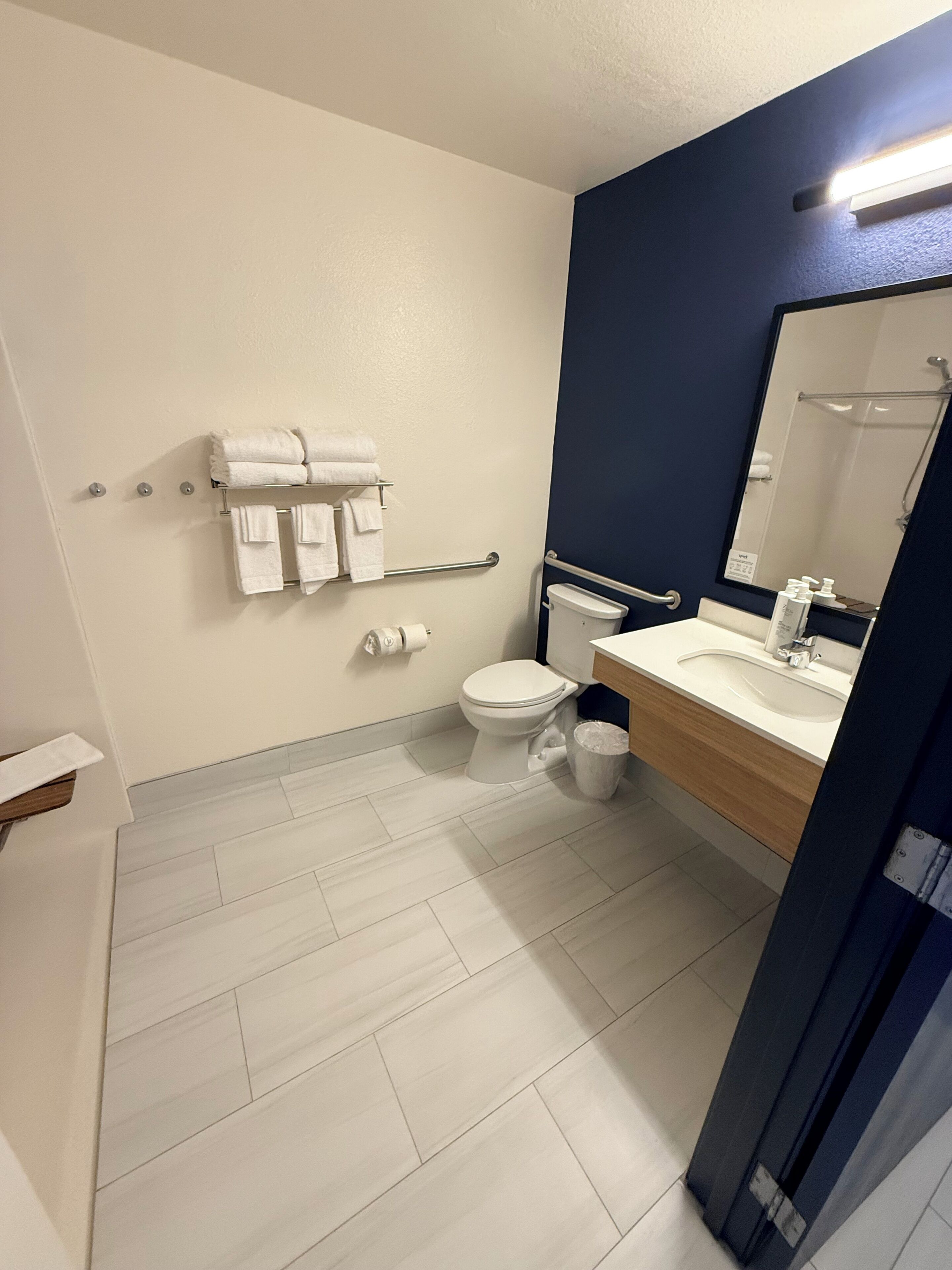 A bathroom with a white toilet, a sink with a mirror, and a towel rack with towels.