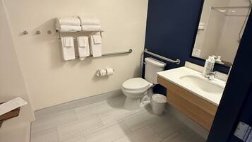 A bathroom with a white toilet, a sink with a mirror, and a towel rack with towels.