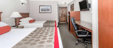 A hotel room with two beds, a desk, a chair, a television, and a framed picture on the wall.
