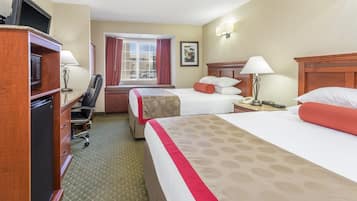 Une chambre d’hôtel avec deux lits, un bureau équipé d’un ordinateur, une chaise et un téléviseur.