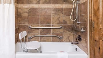A bathroom with a bathtub, grab bars, a showerhead, and a towel rack.