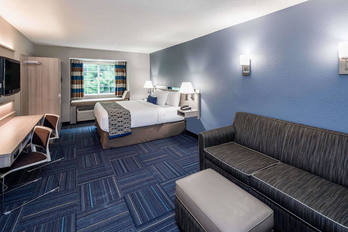 Ein Hotelzimmer mit Bett, Sofa, Schreibtisch und Fernseher.