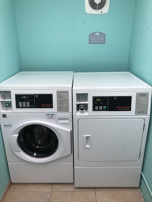 A laundry area with a front-loading washer and a top-loading dryer. - Microtel Inn & Suites by Wyndham Greenville / Woodruff Rd (Greenville)