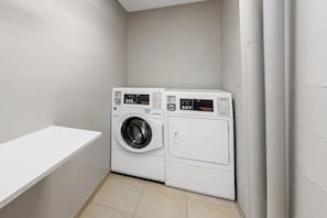 A laundry room with two stacked washing machines and a single dryer. - Microtel Inn & Suites by Wyndham Greenville / Woodruff Rd (Greenville)