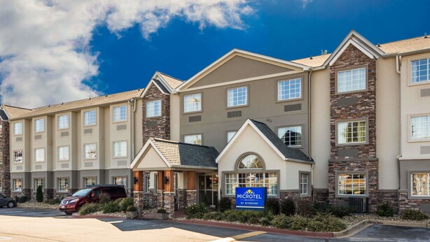 A hotel with a stone facade, multiple windows, and a sign indicating it's a Wyndham hotel. - Microtel Inn & Suites by Wyndham Greenville / Woodruff Rd (Greenville)