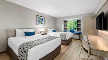 Habitación de hotel con dos camas, un escritorio, un televisor y una ventana con cortinas.