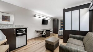A compact living space with a kitchenette, a flat-screen TV, a sofa, and a bed with a patterned cover. - Microtel Inn & Suites by Wyndham Greenville / Woodruff Rd (Greenville)
