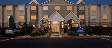 A hotel with a central entrance, multiple windows, and a flag.