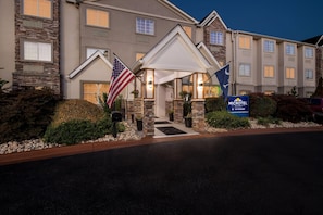 A hotel entrance with stone facade, American flag, and a sign for Microtel Inn & Suites by Wyndham. - Microtel Inn & Suites by Wyndham Greenville / Woodruff Rd (Greenville)