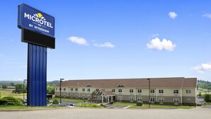 A Microtel Inn by Wyndham building with a large sign, parking lot, and a well-maintained lawn. - Microtel Inn By Wyndham Mineral Wells/Parkersburg (Mineralwells)