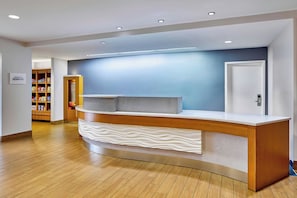 A reception desk with a modern design, a wooden counter, and a blue wall in the background.