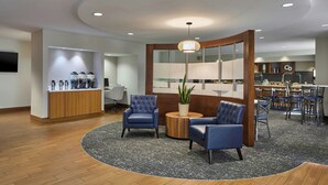 Una hall moderna con un'area salotto a forma circolare, una reception e un'area ristorazione.