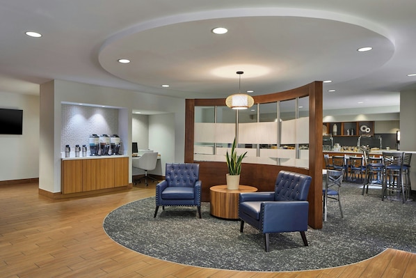 A modern lobby with a round seating area, a reception desk, and a dining area. - SpringHill Suites by Marriott Atlanta Alpharetta (Alpharetta)