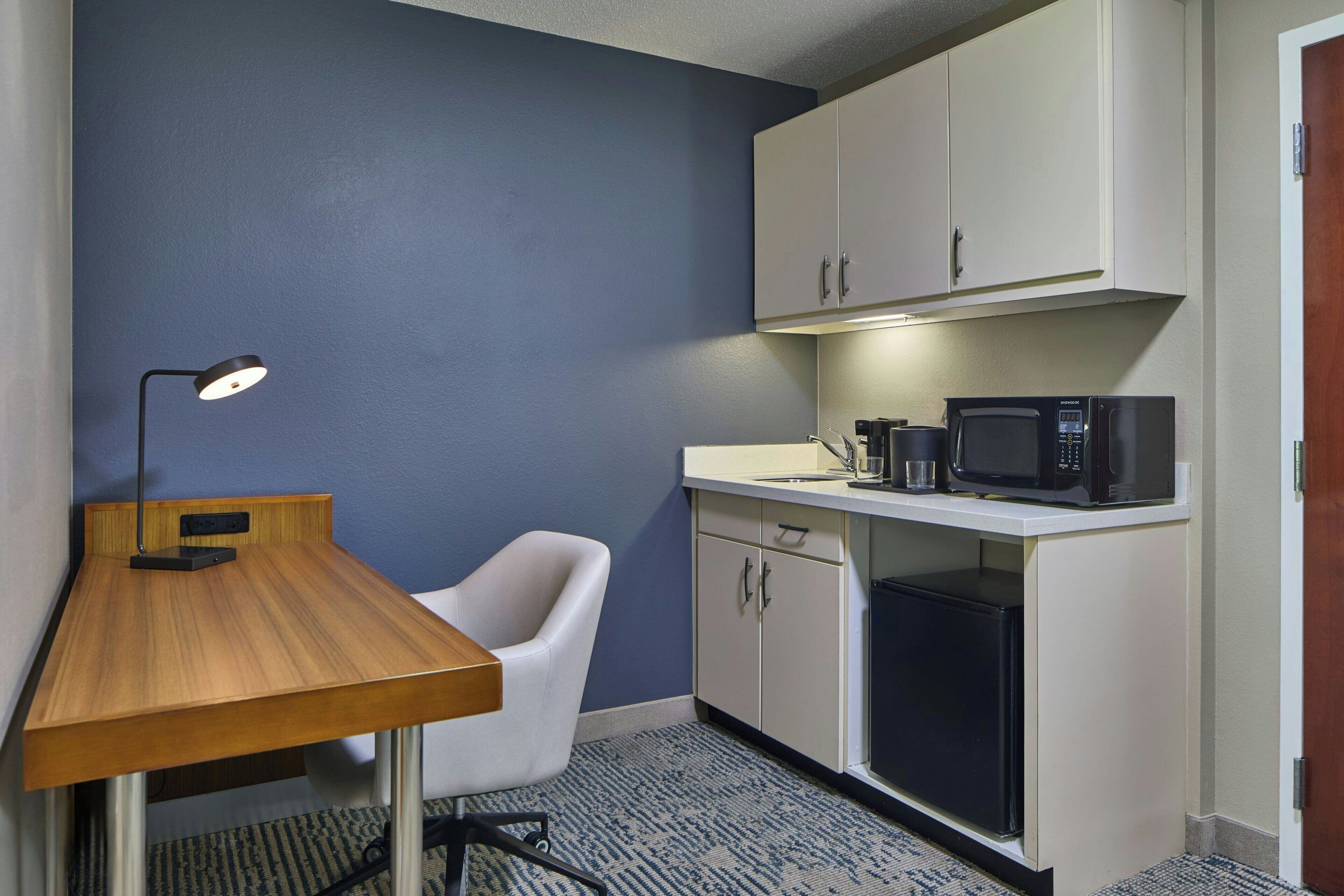 A compact kitchenette with a microwave, coffee maker, and a small refrigerator.