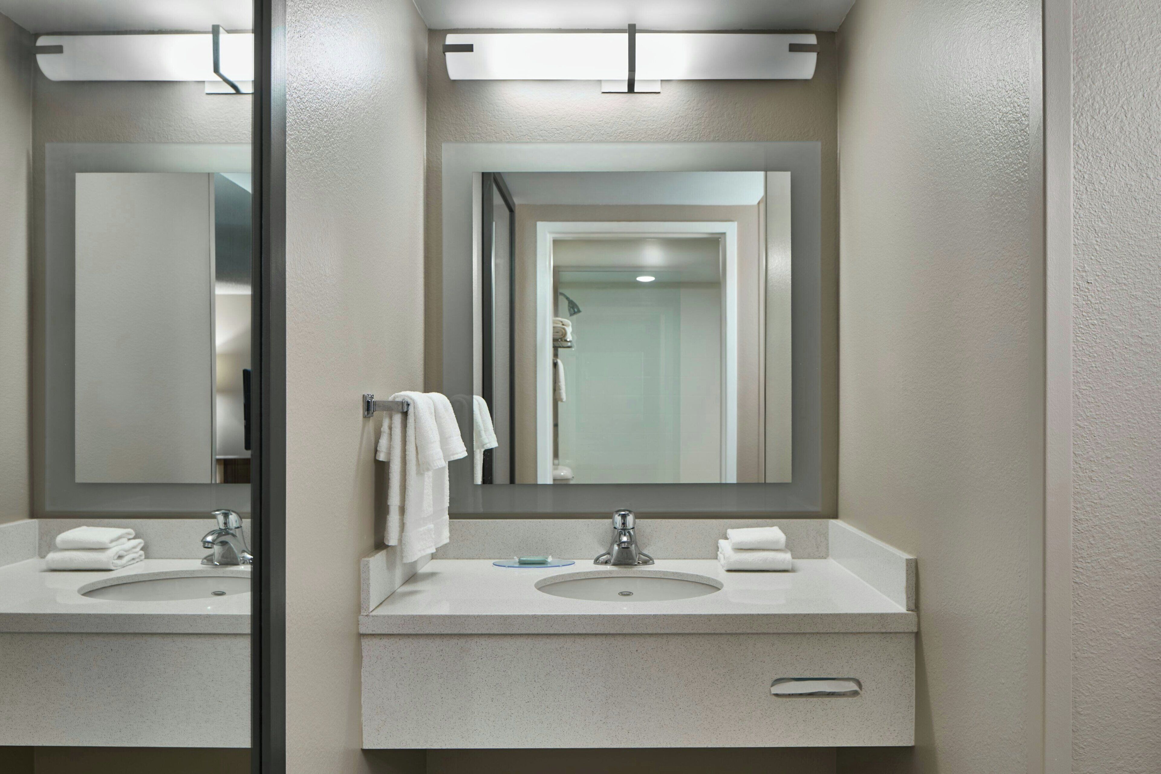 A bathroom with two sinks, a mirror, and a towel rack.