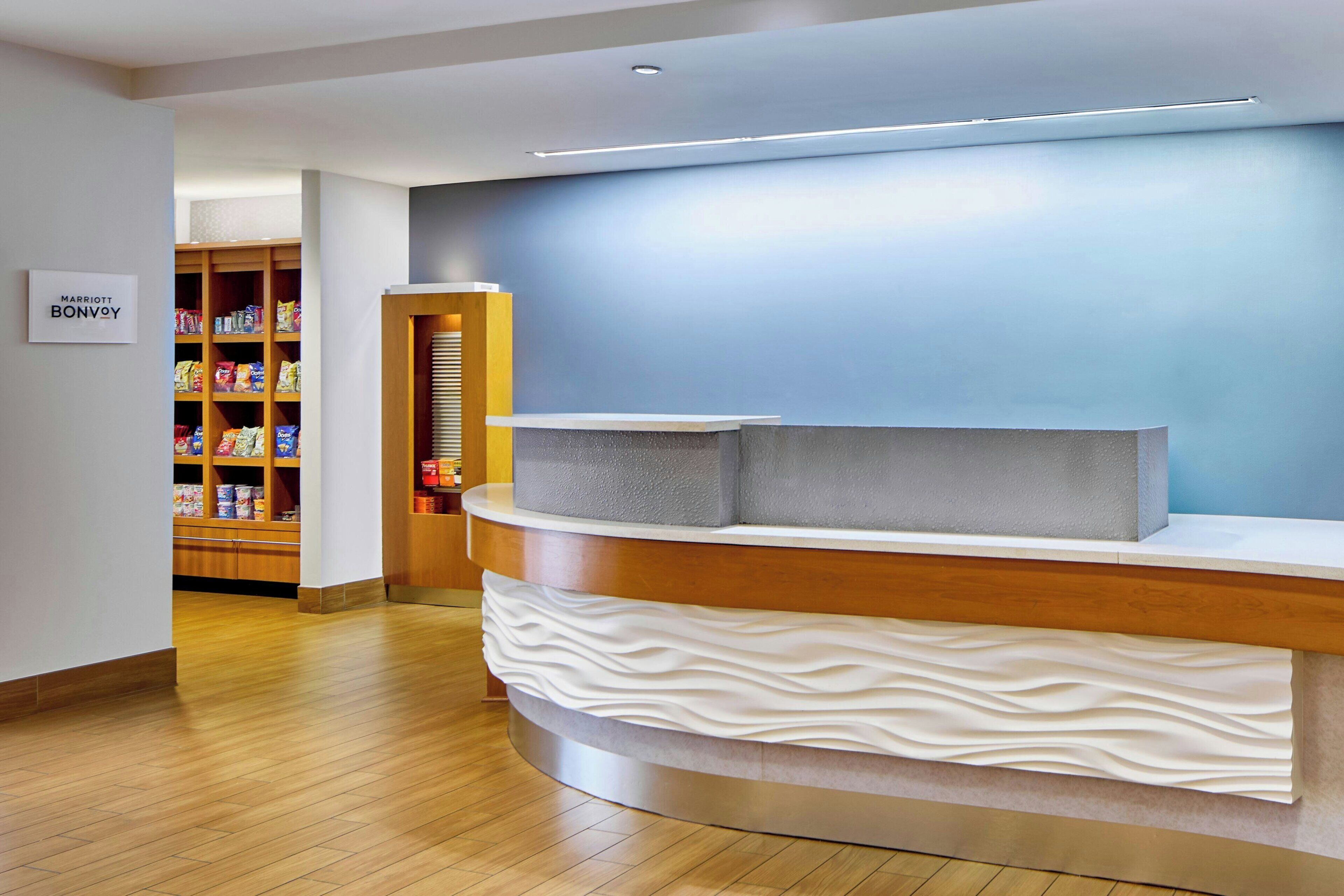 Zona de recepción con mostrador de madera, pared azul y estante con aperitivos.
