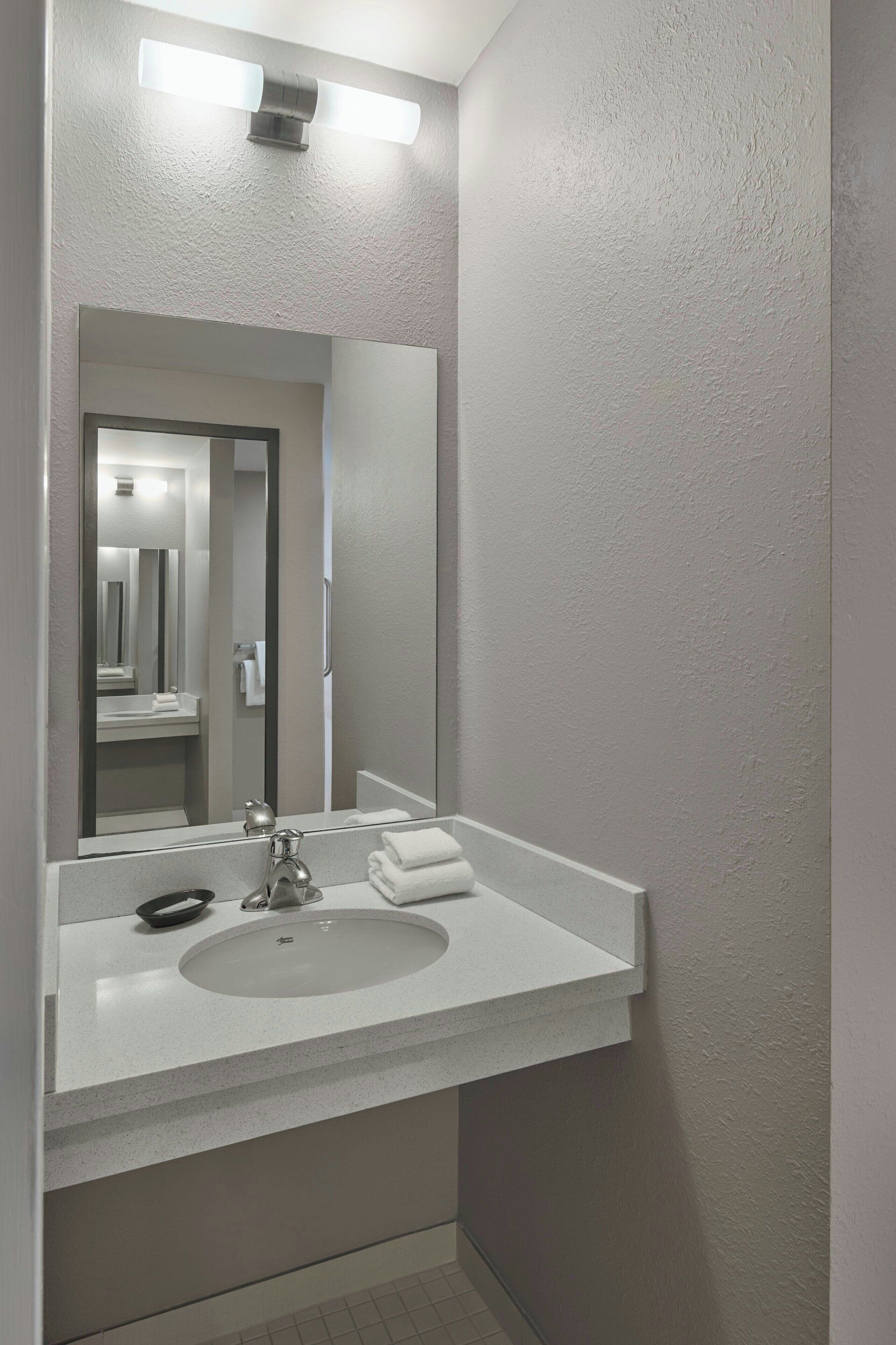 A bathroom with a white sink, a mirror, and a towel rack.
