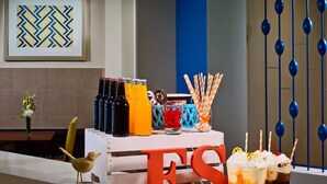 Un coin bar avec des bouteilles de boissons, un oiseau posé sur le comptoir et une enseigne décorative avec les lettres « ES ».