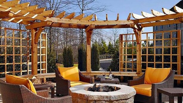 Un espace extérieur aménagé en terrasse, avec des meubles en osier, un foyer en pierre et une structure en forme de pergola.