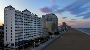 Un hotel con varios pisos y balcones, situado junto a la playa.