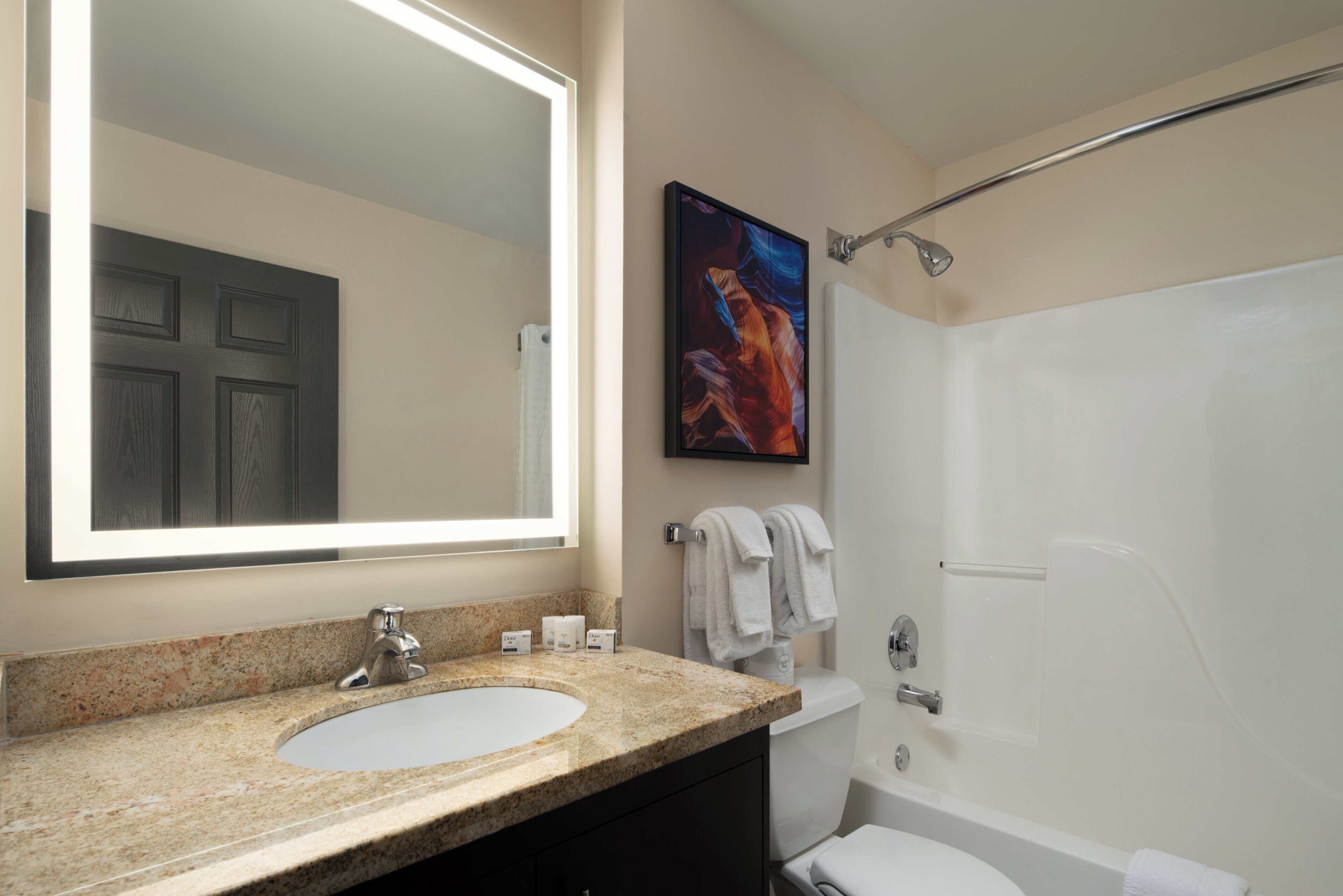 A bathroom with a large mirror, a sink, a toilet, and a bathtub.