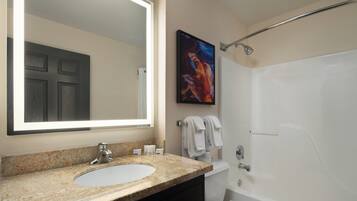 A bathroom with a large mirror, a sink, a toilet, and a bathtub.