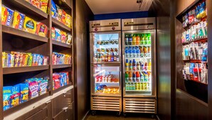 A snack and beverage vending area with multiple shelves of snacks and two refrigerated beverage dispensers. - Courtyard by Marriott Hartford Manchester (Manchester)
