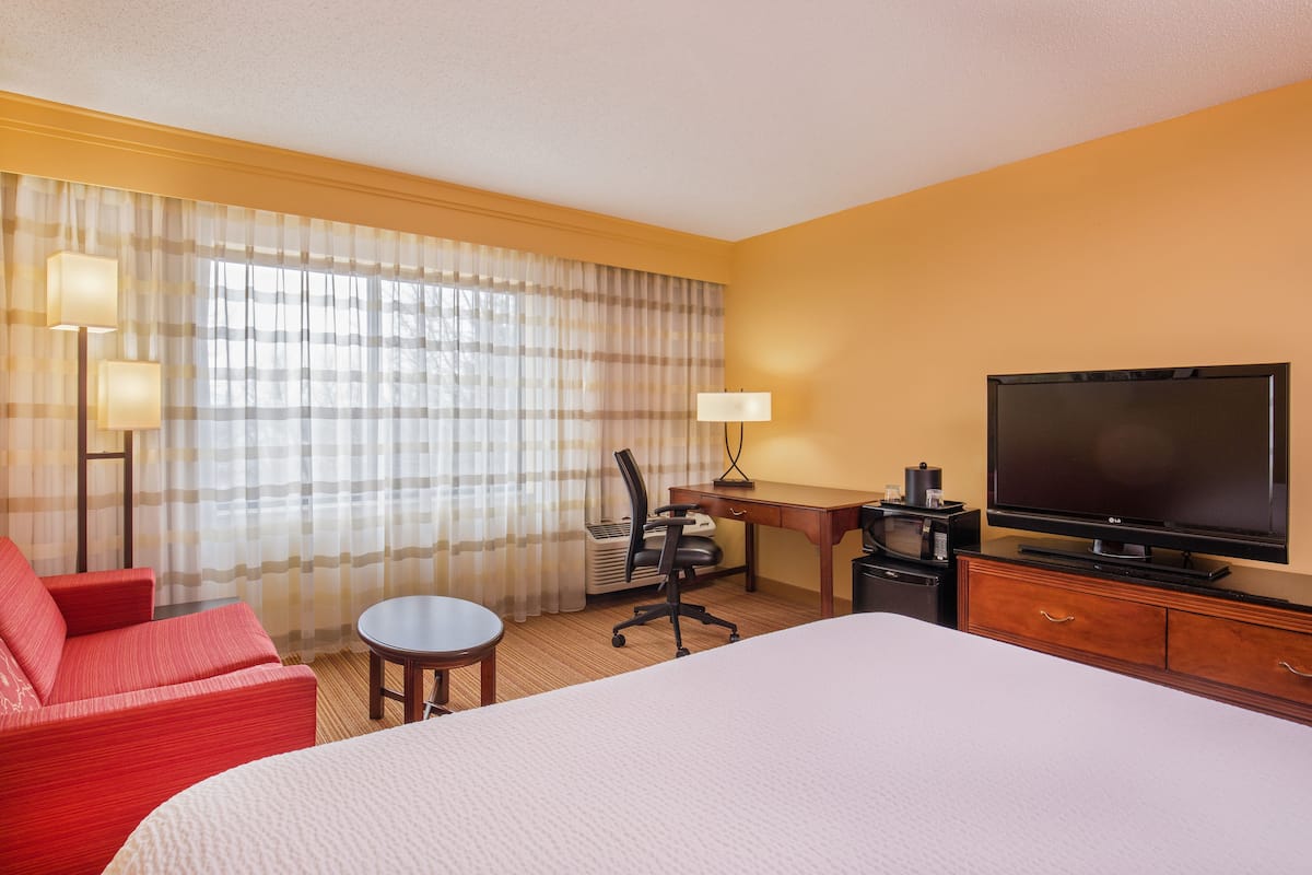 Une chambre d’hôtel équipée d’un lit, d’un bureau, d’une chaise, d’une télévision et d’une lampe.