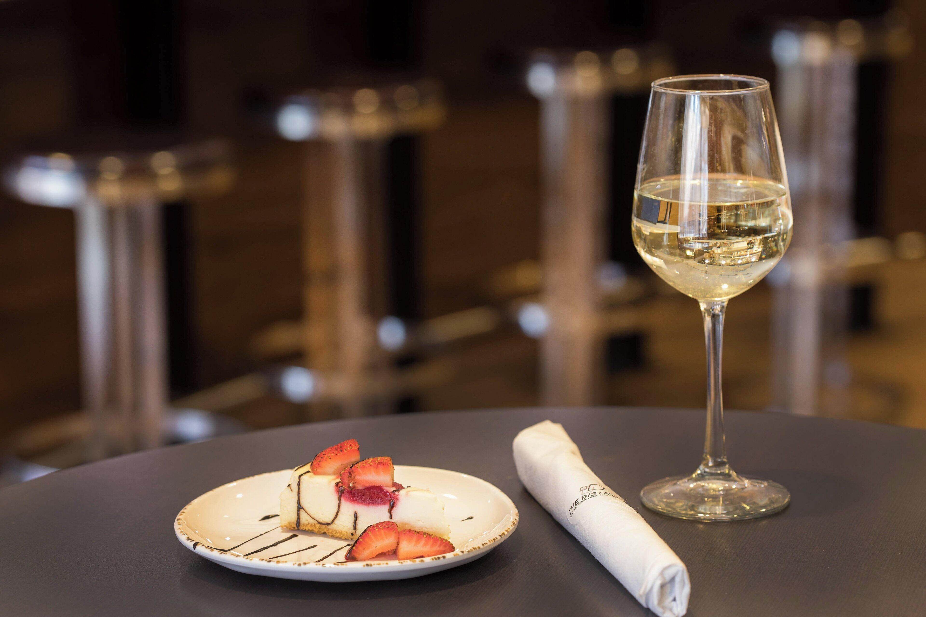 A dessert plate with strawberries and a folded napkin on a table.