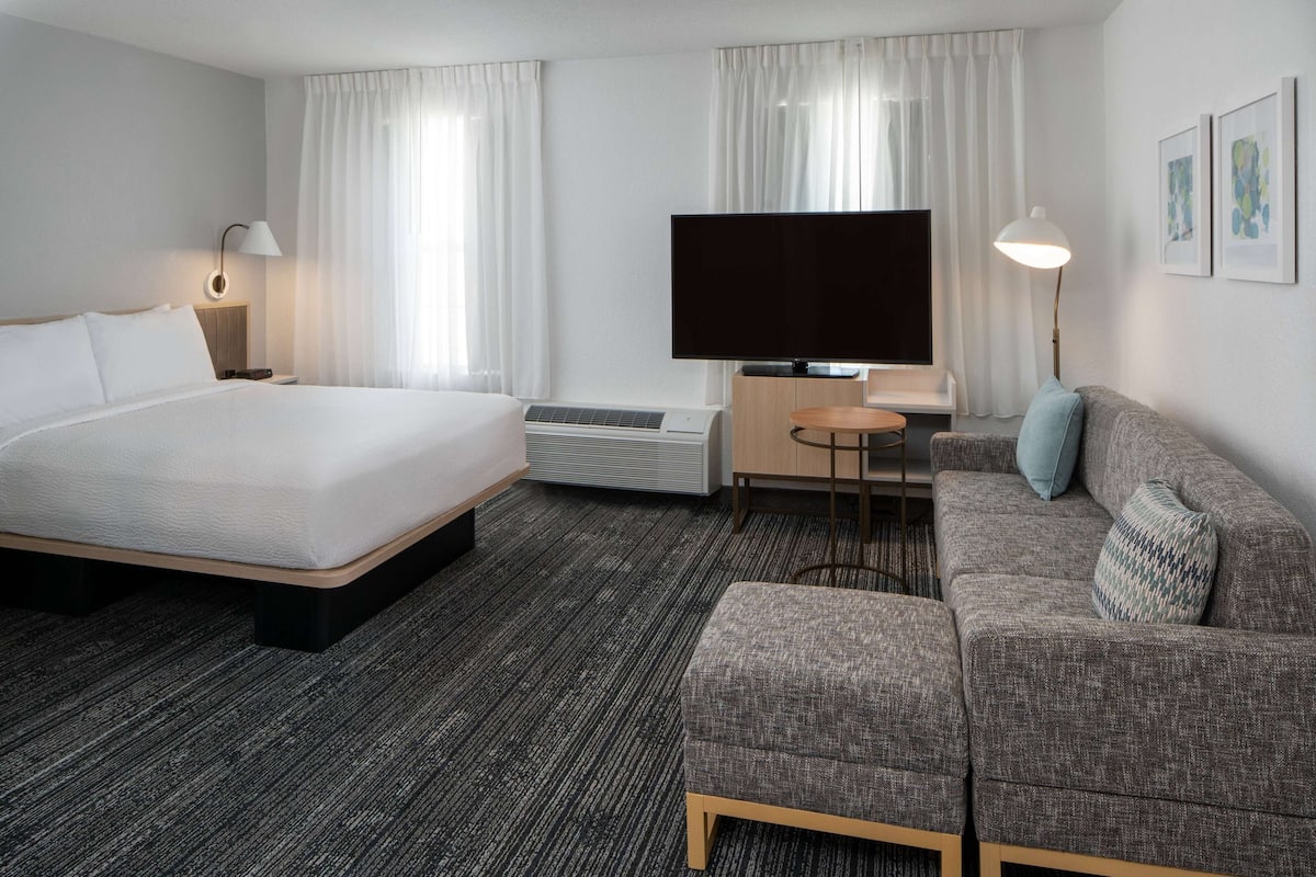 Una habitación de hotel con una cama grande, un sofá, un televisor y un escritorio.