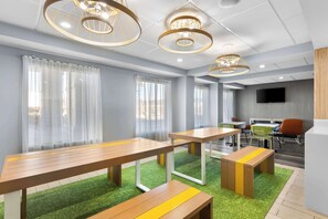 A modern conference room with wooden tables, green artificial grass, and a flat-screen TV on the wall. - Spark by Hilton Calhoun (Calhoun)