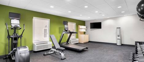 A gym with treadmills, elliptical machines, and free weights.