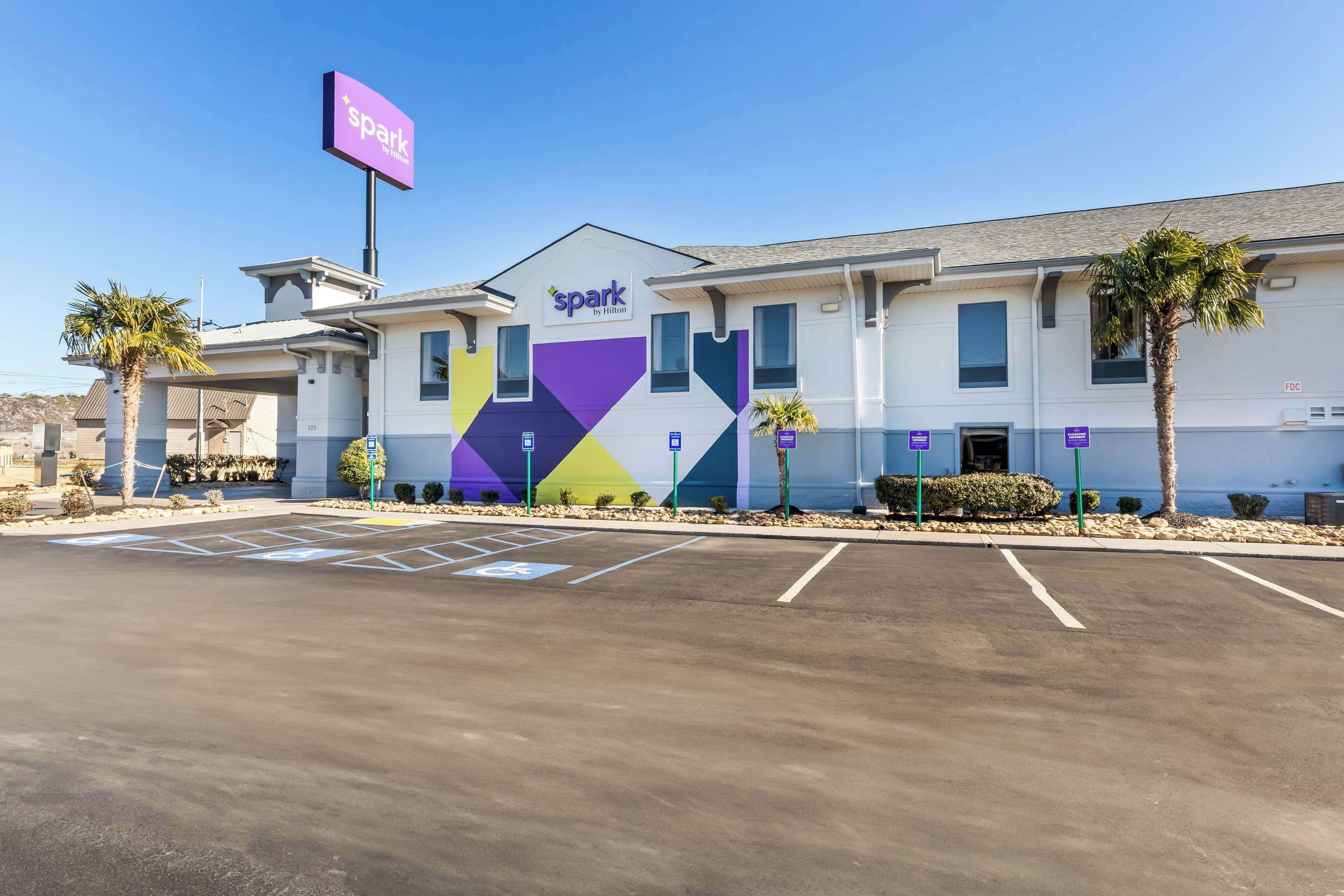 A hotel with a modern design, a parking lot, and a clear sky.