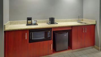 Une cuisine compacte équipée d’un four à micro-ondes, d’une machine à café et d’un réfrigérateur.