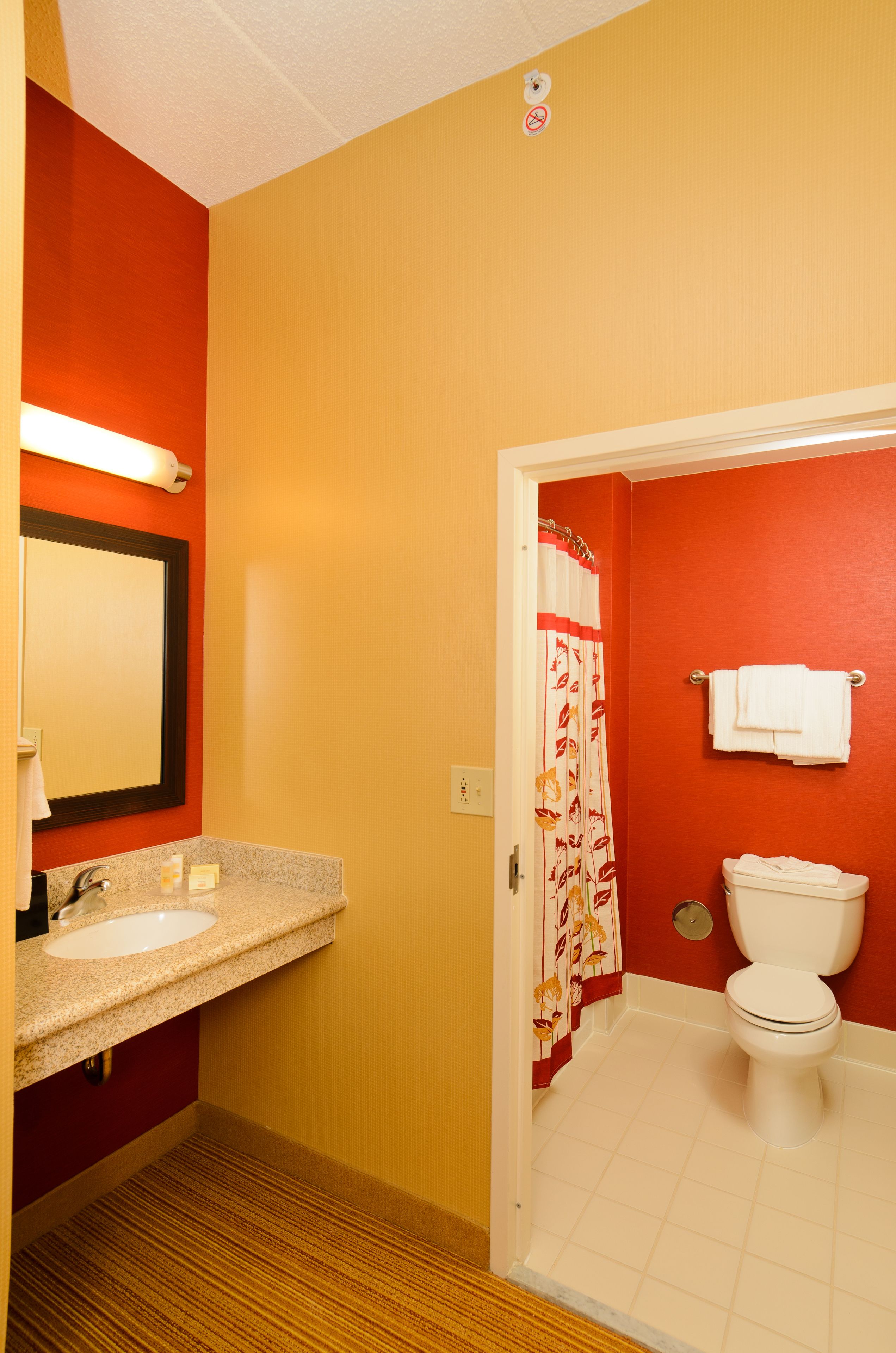 A bathroom with a red wall, a white sink, and a toilet.
