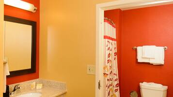 A bathroom with a red wall, a white sink, and a toilet.