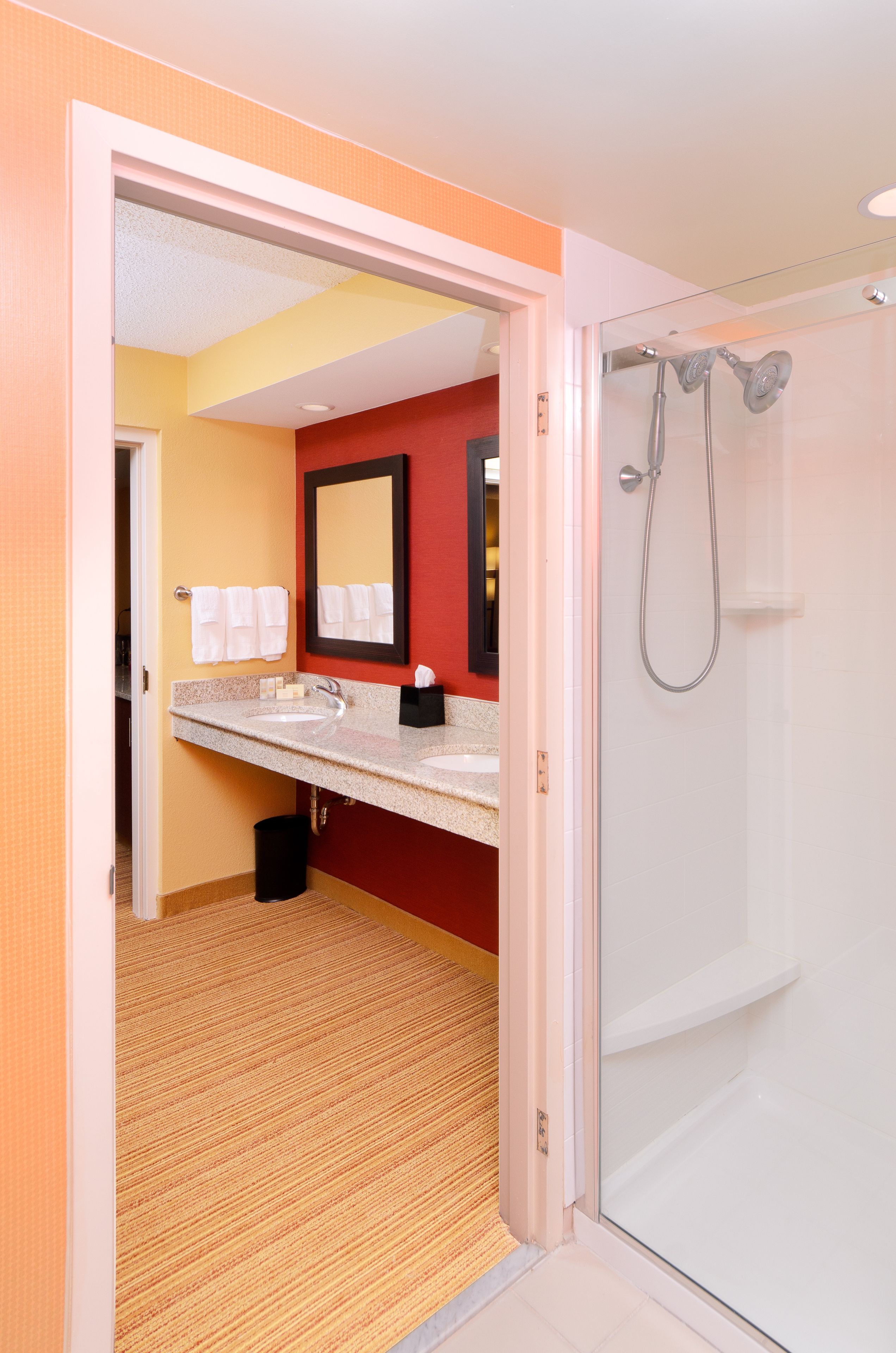 A bathroom with a glass shower, a sink with a mirror, and a towel rack.