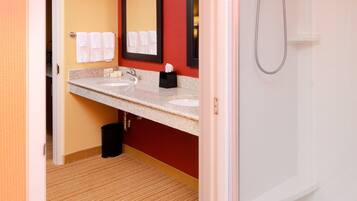 A bathroom with a glass shower, a sink with a mirror, and a towel rack.