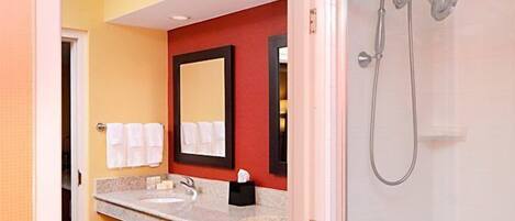 A bathroom with a sink, mirror, and shower.
