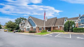 A building with a flagpole, a parking lot with handicapped parking, and a sign that reads "Sonesta."