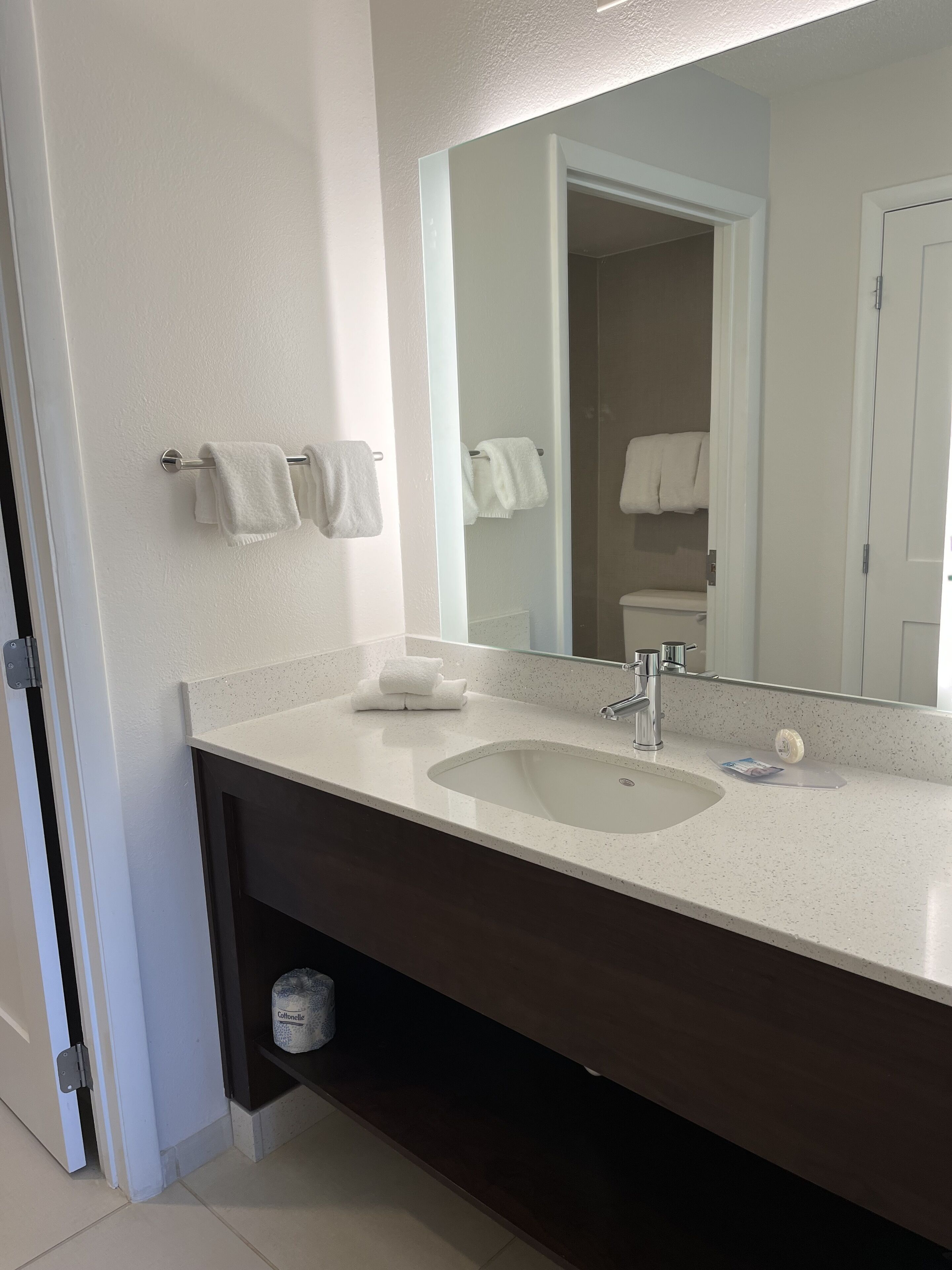A bathroom with a white sink, a mirror, and two towels hanging on the wall.