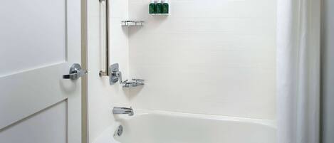 Une salle de bain moderne avec une baignoire blanche, des robinetteries chromées et une étagère contenant des articles de toilette.