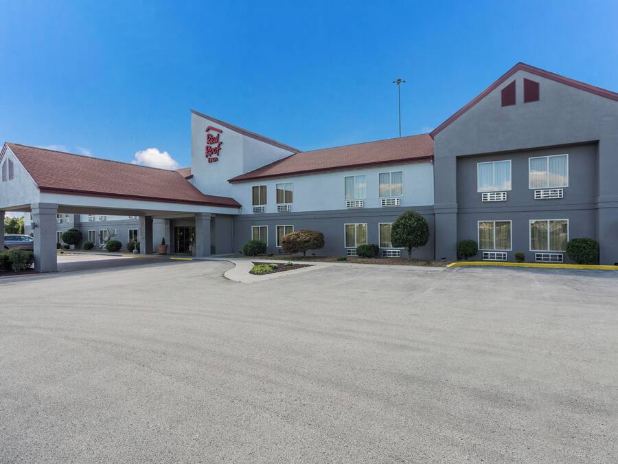 A Red Roof Inn with a covered entrance, a parking lot, and a clear blue sky.