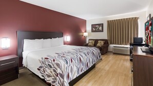 Hotelkamer met een bed, bureau, stoel, televisie en raam met gordijnen.