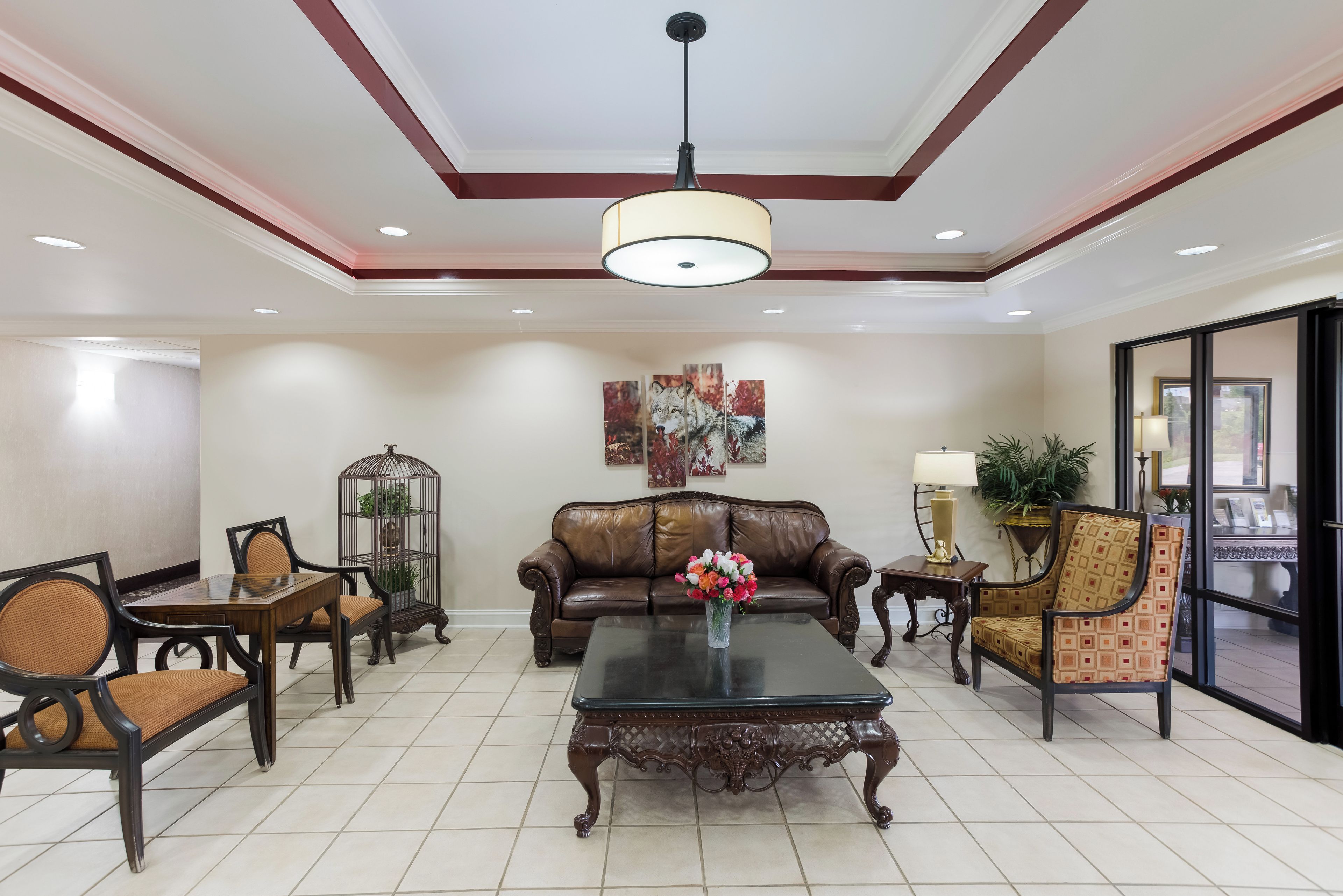 A spacious living area with a leather sofa, a coffee table, and a chandelier.